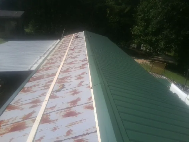 Old rusted panels beside newly installed green metal roofing — Wind Damage Roof Repair by Roofing Brothers in Lemoyne