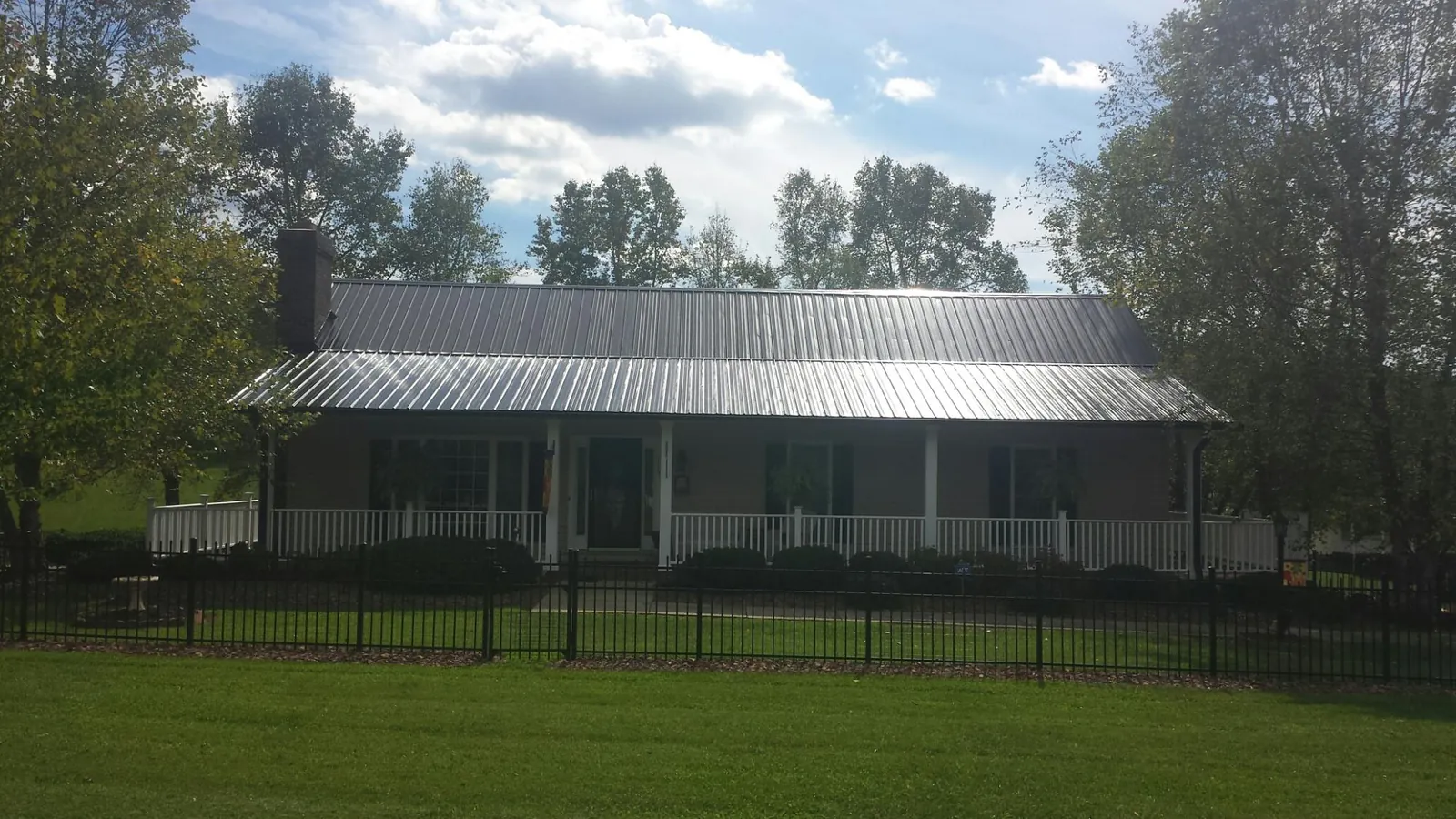 Gray metal roof on a brick ranch with a full width front porch — Gutter Guard Installation work by our crew in Lemoyne