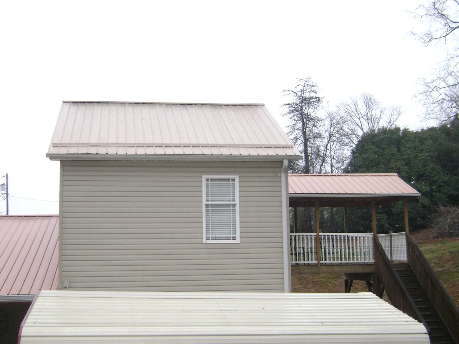 Tan metal roofs on a two story addition and attached porch, from a Roof Replacement job in Lemoyne